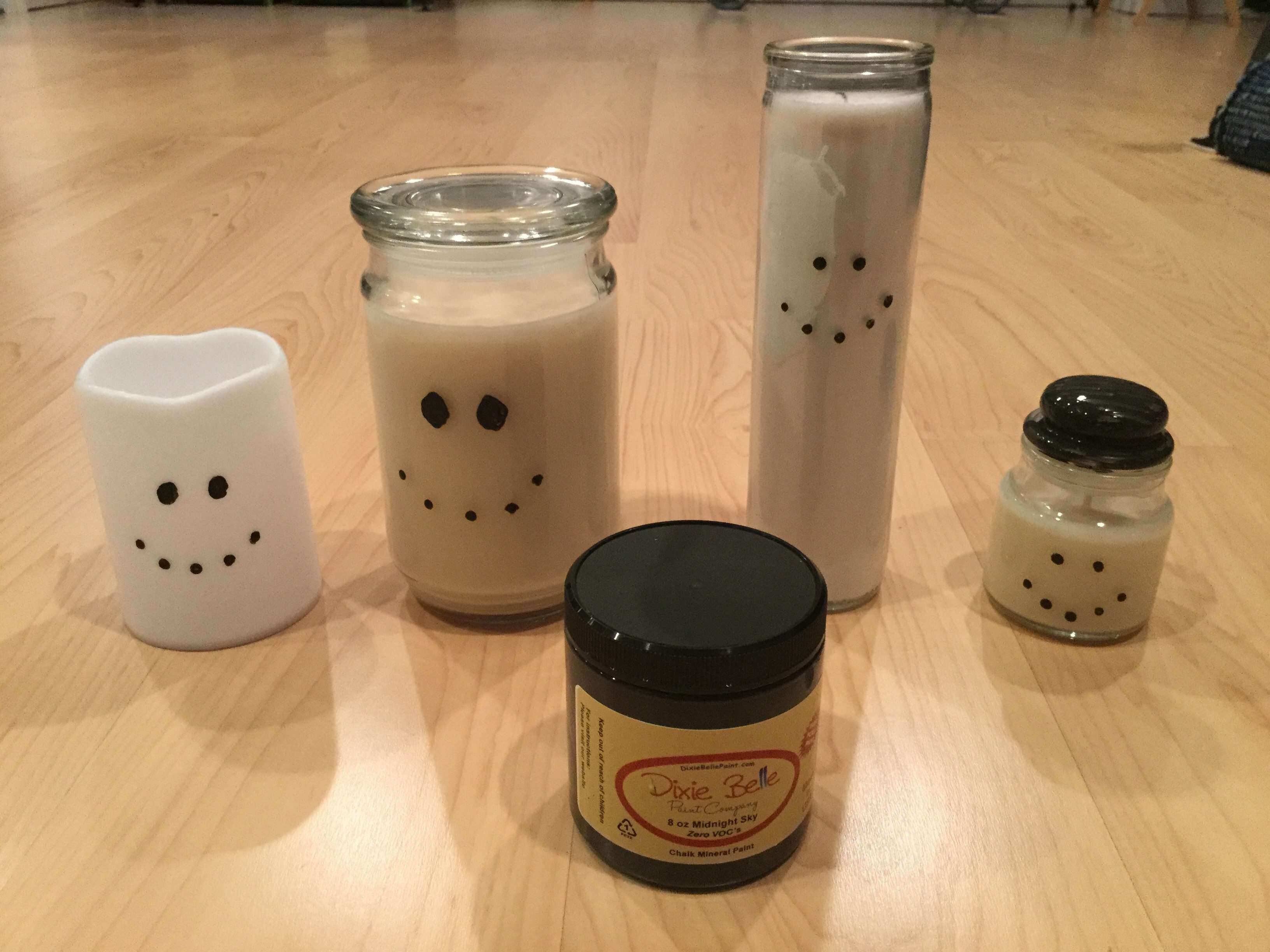 First use black paint to paint on the snowman face of your choice. You’ll see the candle on the right I decided to paint his lid as a hat. The candle on the left is a battery operated candle, but you could do this on pillar candles as well.