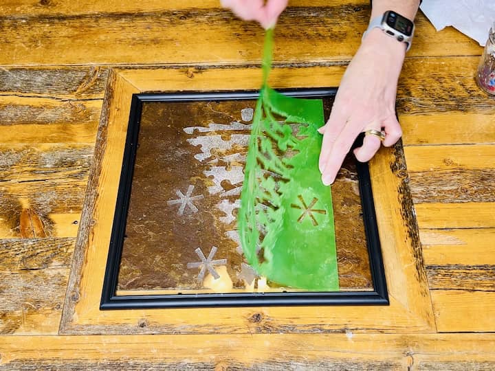 Step 6: Remove Painter's Tape and Stencil Once the entire stencil is coated with window wax, carefully remove the painter's tape holding it in place. Then, gently lift the stencil off the glass surface. Take your time during this step to ensure that the wax design remains intact.