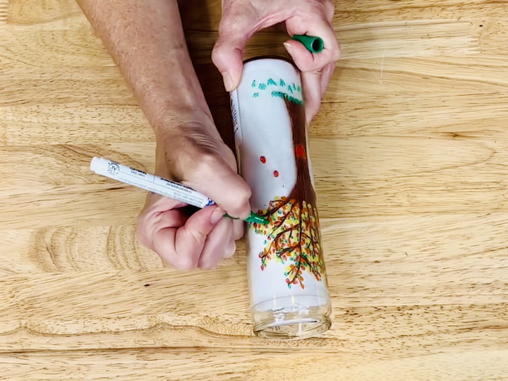 Step 6: Infuse Vibrancy with Leaves Dip into a variety of colors – red, orange, yellow, green, and more – using the corresponding Apple Barrel paint pens. Start adding leaves to the branches, covering the tree with a burst of festive colors.