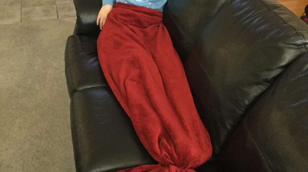 Here is my daughter hanging on the couch with the mermaid/shark tail.  When the kids are done playing with it, take the binder back out for your regular blanket.  If you want it to be permanent you can always cut the tail into the shape you want after putting the binder in.