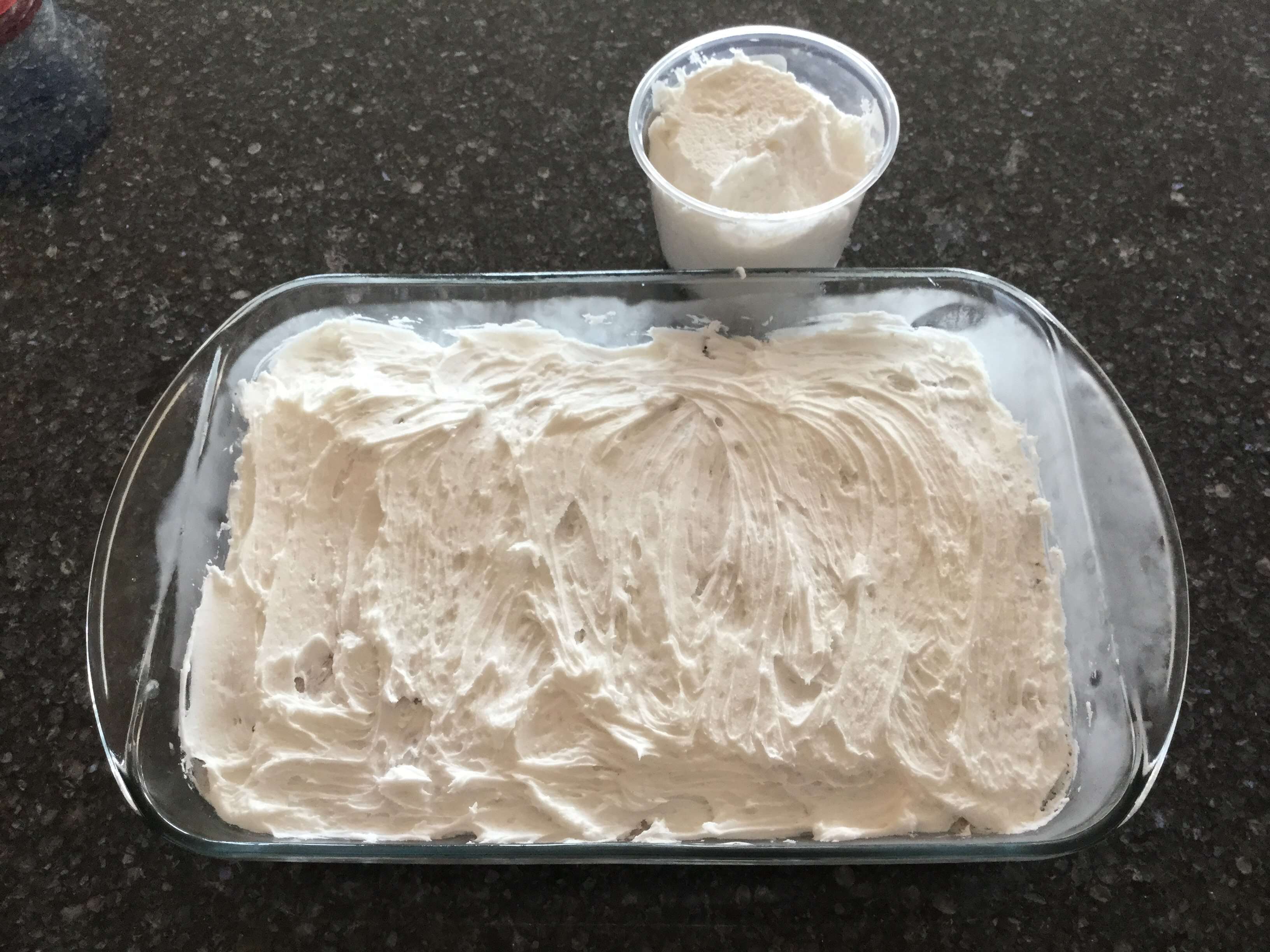 After the ice cream is nice and solid, add your top.  I usually use cool whip and it spreads on nice and smooth.  My son decided he wanted frosting.  Spread which ever you choose and place in the freezer.