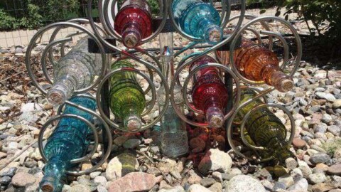 I added 3 solar lights from the Dollar Tree between the bottles. The lights on the right and left are stuck into the ground. The one in the middle I wanted a little higher so I removed the stake and put it in a clear mini bottle.  After looking at this for a period of time I ended up adding crystal beads to the front to look like it was pouring.