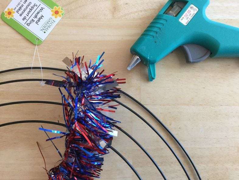 Hot glue your tinsel into place at the top of the wreath form.