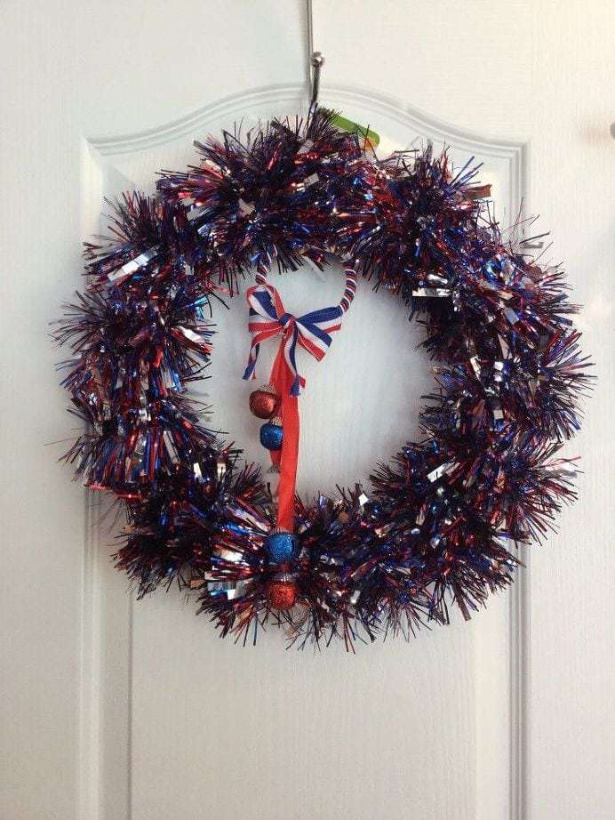 Center your door hanging bell decoration and finish wrapping the tinsel. When you get to the end, hot glue the end into place at the top.