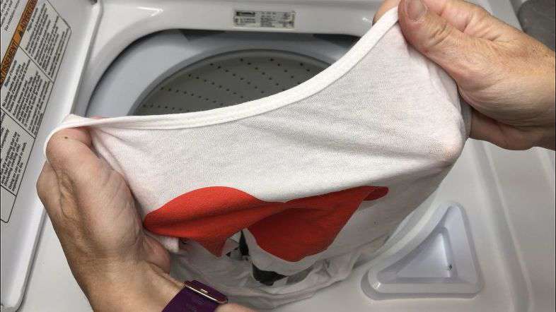 Placing shirt in washing machine. 