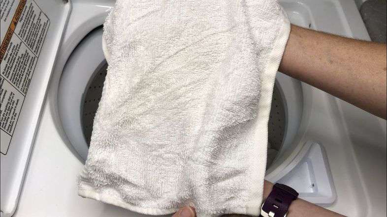Placing towel in washing machine.