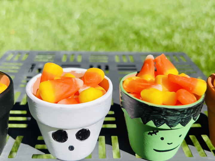Fill each flower pot with candy corn or your favorite Halloween candies. These flower pots can serve as adorable snack holders for your Halloween table or party.