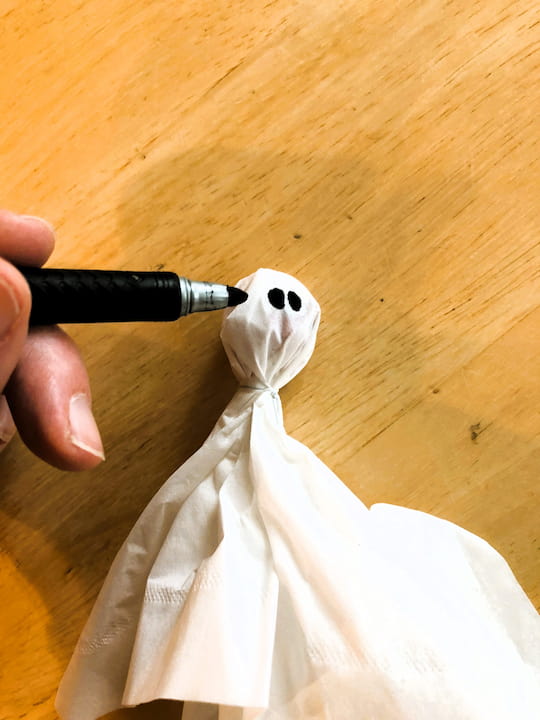 I placed a lollipop into the center of a tissue.  I wrapped the tissue around the lollipop and secured it with a twist tie, and you could alternatively use string.  I drew on 2 eyes.  This makes a great party favor, and kid's craft.