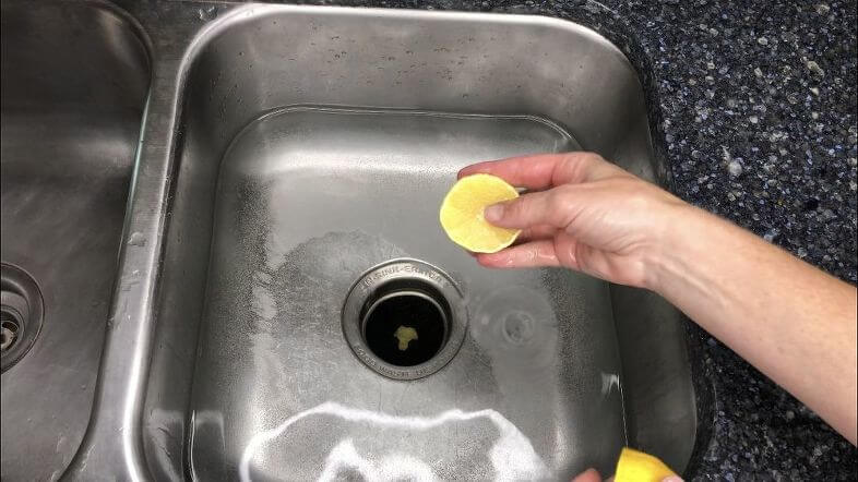 Slicing a lemon and putting it in the garbage disposal to unclog kitchen sink.