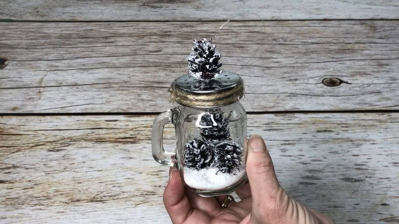For my other matching shaker - I attached the string through the holes, added some Epsom salt to the bottom of the shaker, placed 3 mini pine cone ornaments into the jar on top of the Epsom salt. I hot glued a little twine around the lid, and topped it with a mini pine cone on the lid.