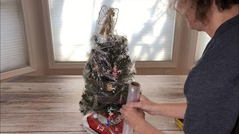 I have a smaller tree that goes in my room. I wrap the entire thing - ornaments and all with saran wrap. This keeps the ornaments in place for next year and keeps the dust off.