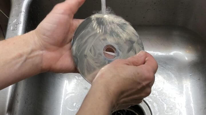 You can rinse CDs and DVDs under the faucet, then use a cotton cloth to lightly dry them.