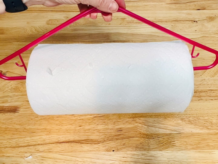Take a plastic hanger and cut the bottom in half. Open up the bottom and slide paper towels onto the hanger, then you can hang the paper towels where you need them. I have hooked this to my workbench and now it's really easy to grab towels when I need them to clean up a mess or wipe up my counters.