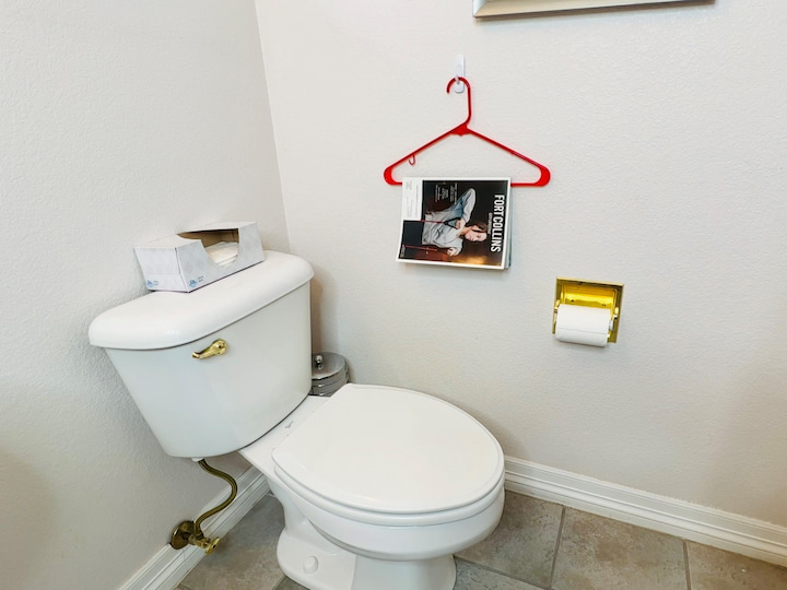 Don't want to bend a wire hanger, no problem.  You can use a command hook and plastic hanger.  Place a command hook on your bathroom wall and put a hangar on the command hook. Now you can use it to hold a magazine.