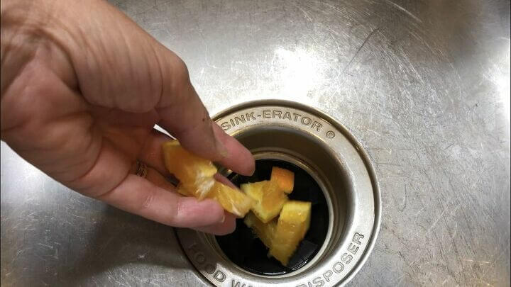 Cut up citrus of your choice - I'm using an orange from the simmering slow cooker from above - and place in your garbage disposal. Run the water and turn your garbage disposal on. Your garbage disposal will be smelling fresh in no time.