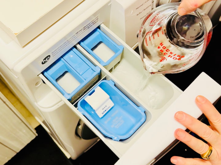 Pouring vinegar into the prewash compartment of washing machine