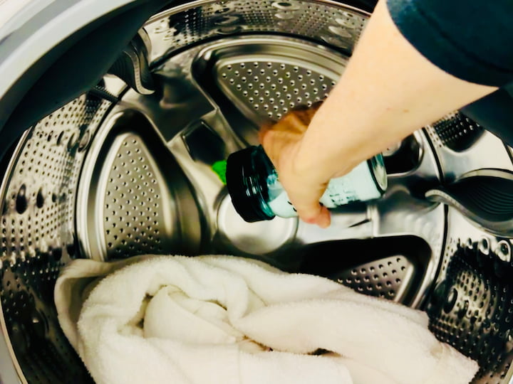 Pouring baking soda onto towels in washing machine