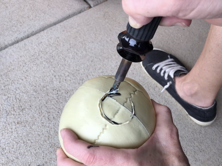 Remove the base from a solar light , and draw a circle onto the skull.  Use a wood burning tool to cut through the plastic and remove the circle.