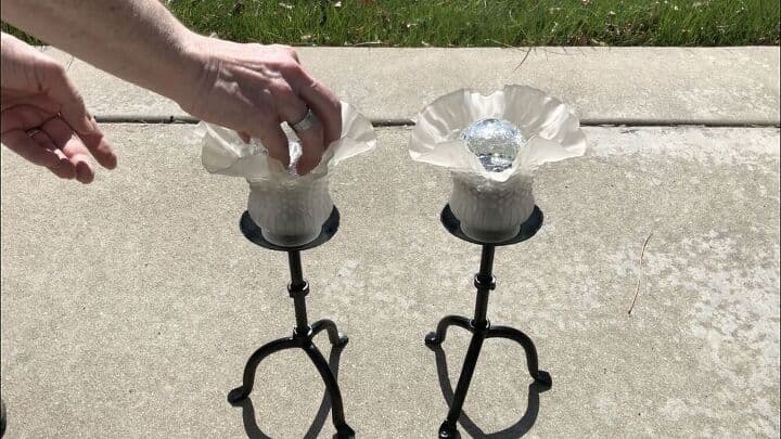 Once the paint dried, I put some old glass light fixtures on top of the candle holders and adhered them with silicone. I pulled the base off of 2 globe solar lights from Walmart and placed them inside the flower.