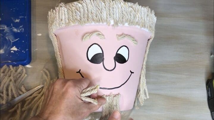 I painted Mod Podge on the rim, sides, and back of the flower pot. I added pieces of mop for the hair.