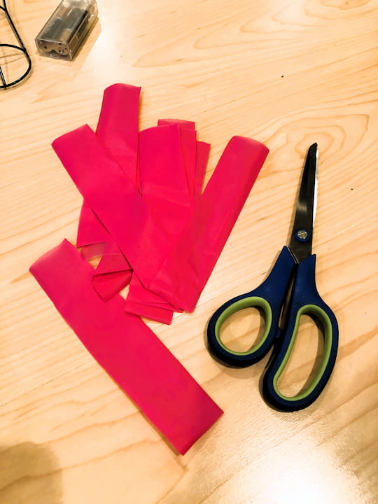 Cut the pink tablecloths into small strips.