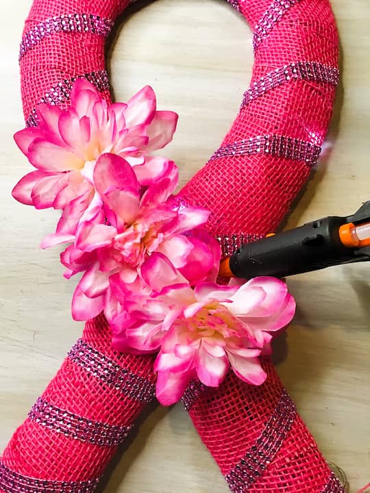 Remove flowers from the stems.  Hot glue pink flowers onto the ribbon to cover any gaps.