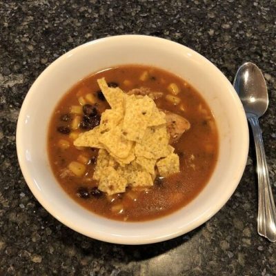 To serve, place soup in a bowl, top with shredded cheese and crushed tortilla chips.
