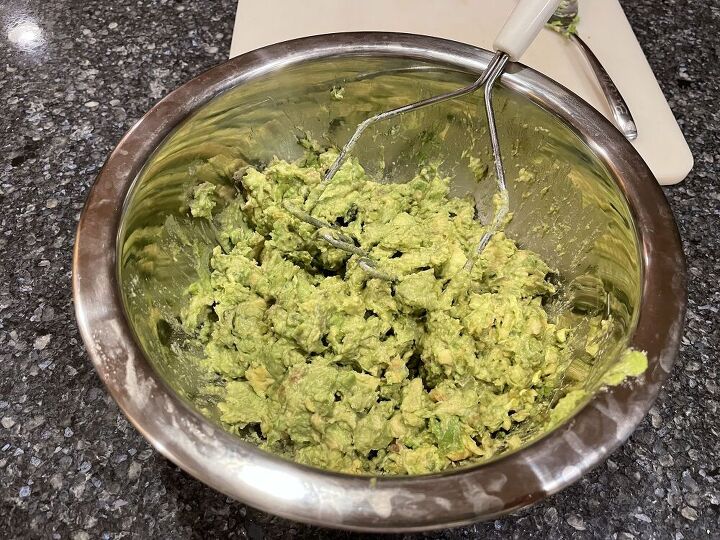 Place the halved avocados in a bowl and mash with a potato masher.