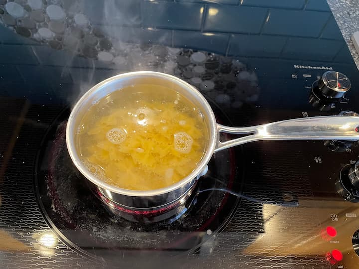 On a stove top bring a pot of water to a boil.  Boil the pasta for 7-9 minutes, drain, and rinse.  