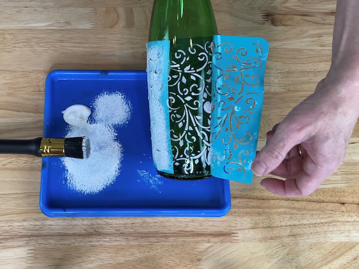 While the paint is still wet, carefully remove the stencil from the bottle.  It's important to remove the stencil right away so that the paint doesn't stick to the stencil and peel off the bottle when lifting.