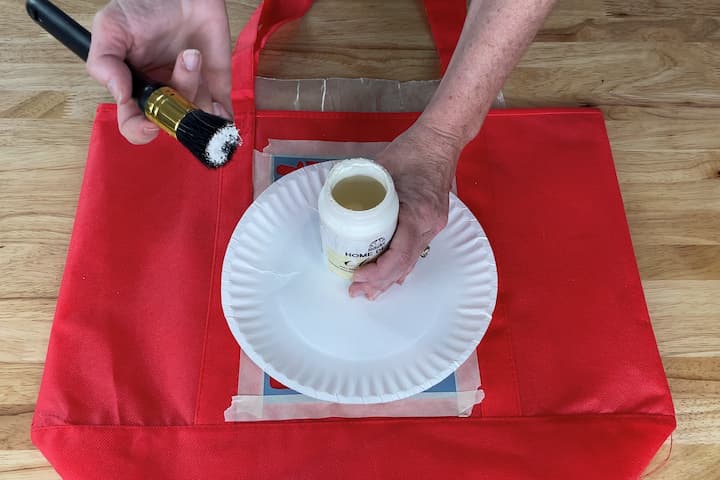 I loaded my stencil brush with paint.  Loading means to get paint on your brush.  I'm using Folk Art Home Decor Chalk paint in the color Sheepskin.  Read the back of paint to make sure it's good for fabric.  If you want to be able to wash the fabric, look for that on the bottle as well.
