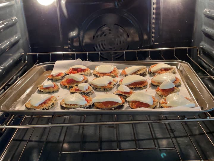 Remove the eggplant from the oven.  Place a spoonful of spaghetti sauce on the eggplant, and then a slice of cheese on top.  You can also use shredded cheese.