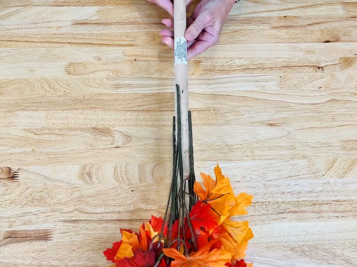 Apply hot glue to the top of the toilet plunger. Gently attach faux leaves to the hot glue, allowing it to set. Repeat the process on the other side and work your way down the plunger.