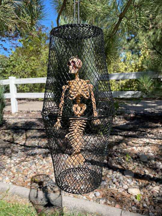 Dollar Tree Halloween crafts, I created a second cage and this time I put a skeleton mermaid from Dollar Tree inside the cage.  I used black paracord to tie the trash cans together and hang the cage.