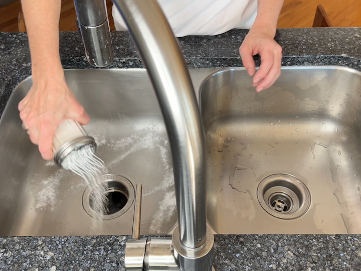 I get my sink wet, and then I sprinkle some baking soda into my sink.