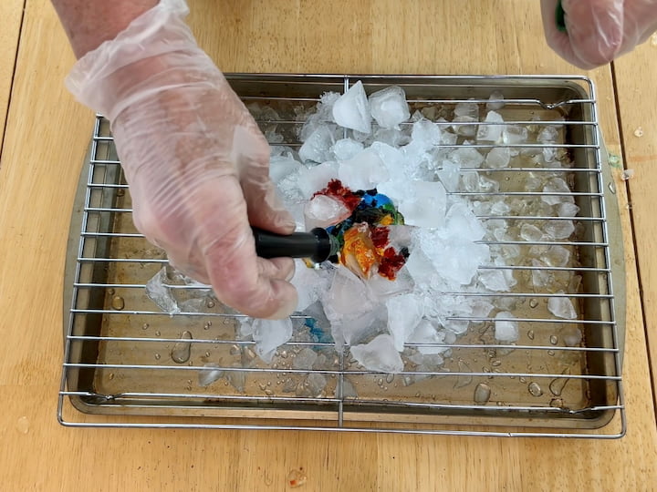 Place the egg onto the ice and food coloring Surround and cover the egg with more ice Add drops of food coloring over the ice