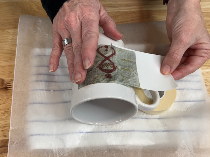 Remove the water decal from the water.  Slide the backing out while placing the transfer onto the mug.