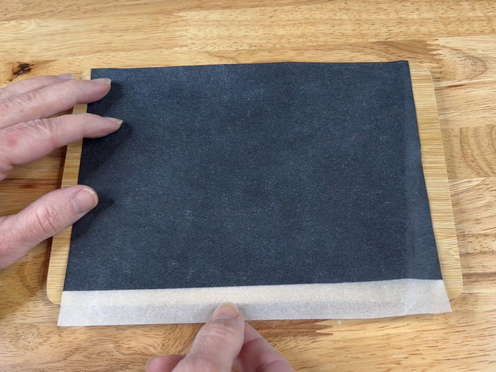 Put a piece of transfer paper over the top of the cutting board.  Use enough that the whole message will fit on it, and place the ink side down on the cutting board.