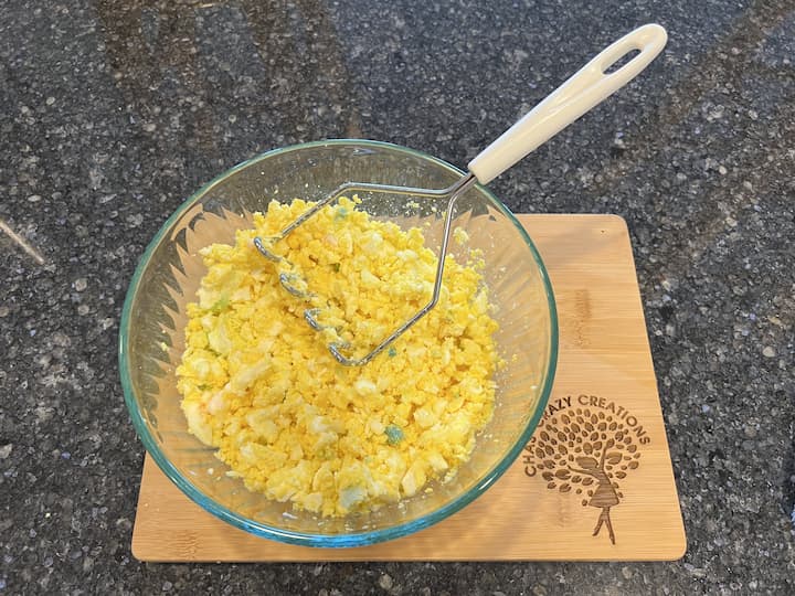 Peel the eggs, rinse them off, and place them in a bowl. Mash the eggs into small pieces. I like using a potato masher to get the job done quickly.