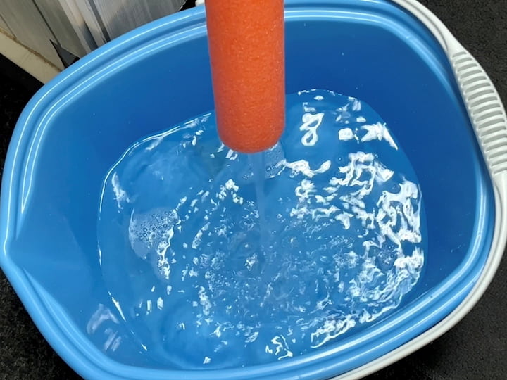 I placed the other end of the pool noodle into the bucket.  I turned the water on and watched the water flow easily into the bucket to fill it up.  This bucket happens to be on wheels which I love so it's super easy to move around.