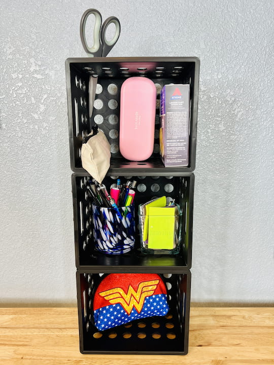 For this example, I'm creating extra storage organization for the bottom of a school locker.  This space is often under utilized and by adding some crates I can gain some fantastic extra storage. I've added charging cords to the bottom, post-it notes pens and pencils to the middle, and a pencil pouch, scissors, glasses, and snacks.