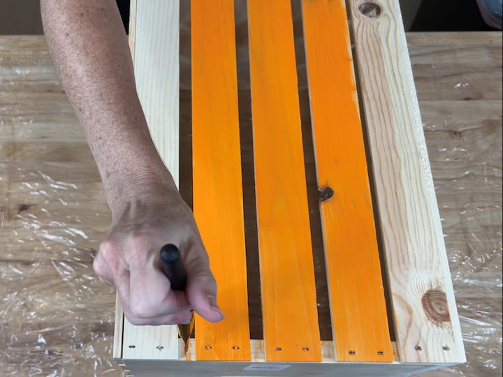 For this first crate, I will be using Apple Barrel paint in the color pumpkin orange. As you can see here I'm just painting the slats with orange paint.