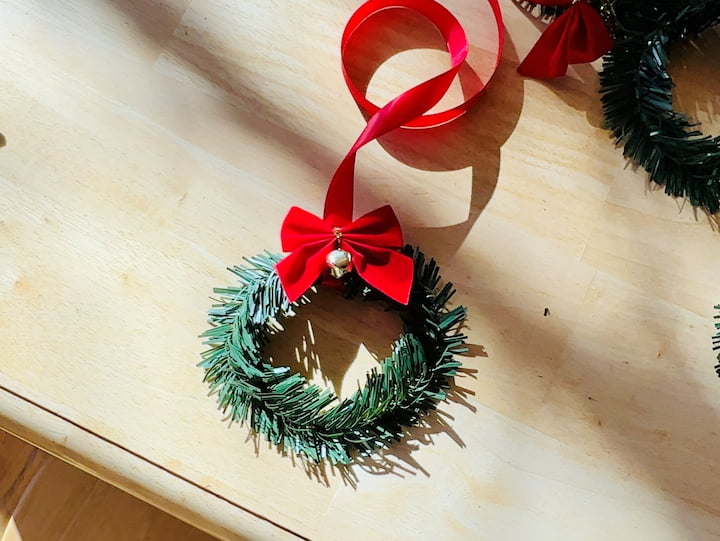 Next I hot glued a little bell and a little bow at the top of each circle, so now I have very festive foliage. I taped the ribbon onto the back of the cabinets and I was ready to hang them all up.