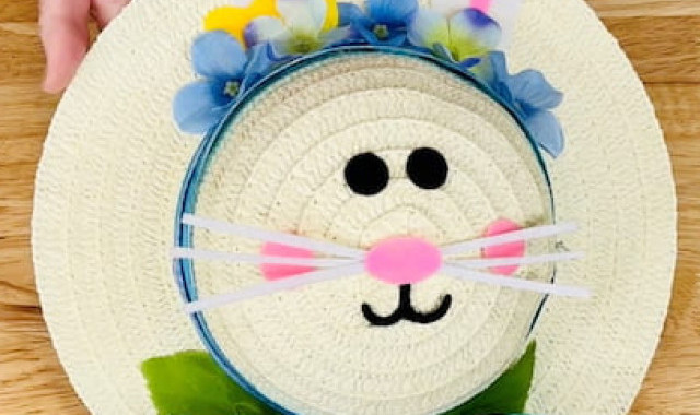 With some of the extra ribbon, I'm going to make a little bow and additional ribbon hanging from the bottom of the hat.  I am adding flowers around the hat and a little bit of the greenery for spring. Once that is where I want it I will glue everything into place. The felt bunny came with a little bow and I thought it was cute so I'm going to tuck it in behind the flowers.