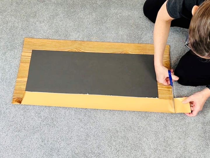 I folded two sides up around the board and pressed them firmly to make them adhere.  Then I took scissors and cut the corners out so that I could fold the remaining sides around the board.  