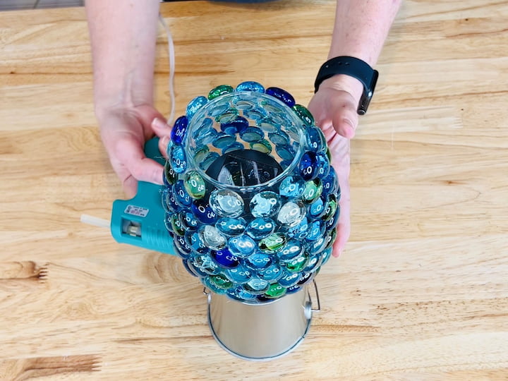 Next, I will take the dollar store bucket and turn it upside down.  I am placing the vase on top of the overturned bucket and I will glue it into place to make sure it is secure.   