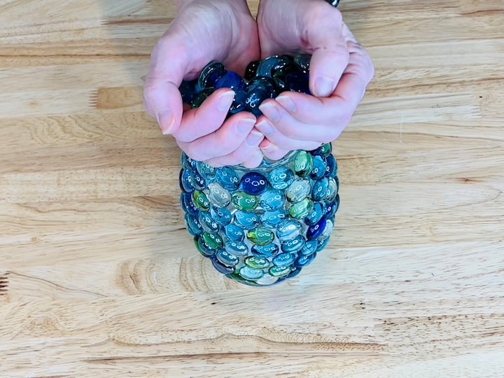 I'm grabbing a couple of handfuls of the dollar store rocks and placing them into the bottom of the vase.  