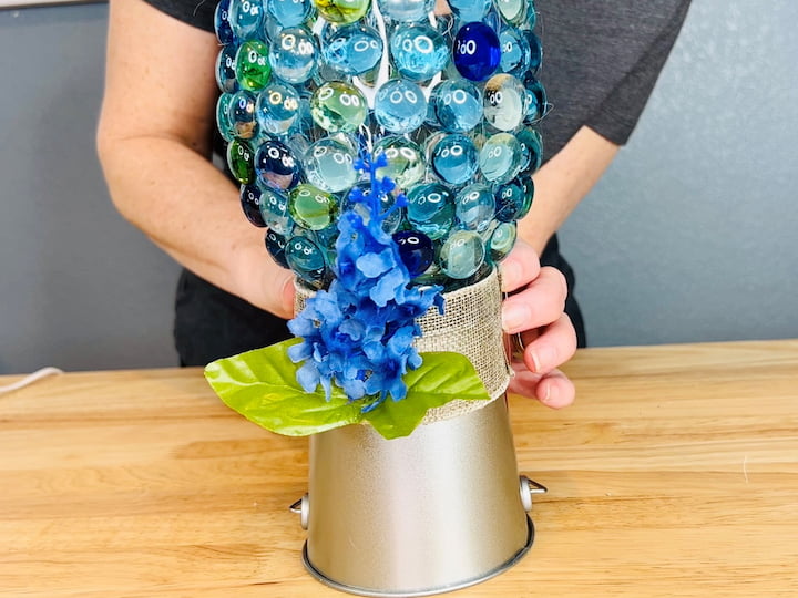 I will wrap the ribbon around where the vase and the bucket come together then hot glue that into place, holding it until it cools.  