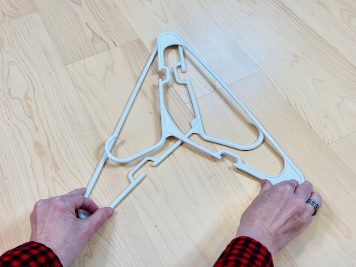 Start with two hangers and place them in this order so that the hooks are up and they're in a triangle shape.  