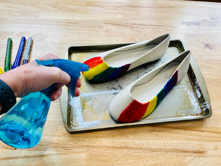 Fill a squirt or spray bottle with rubbing alcohol and start squirting it all over the shoes. The rubbing alcohol will help the colors blend together and create a tie-dye effect.